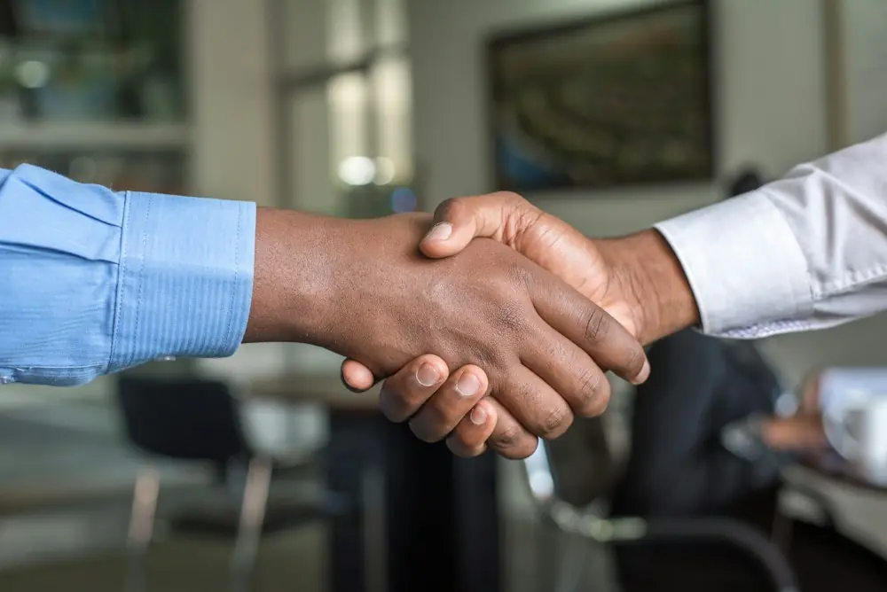 Two partners shaking hands across a table
